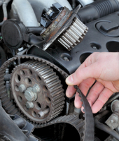A person is holding the belt of a car engine.